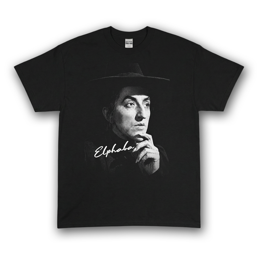 Black tee with high-contrast halftone portrait of Elphaba the Wicked witch wearing a wide-brim hat from Wizard Of Oz.